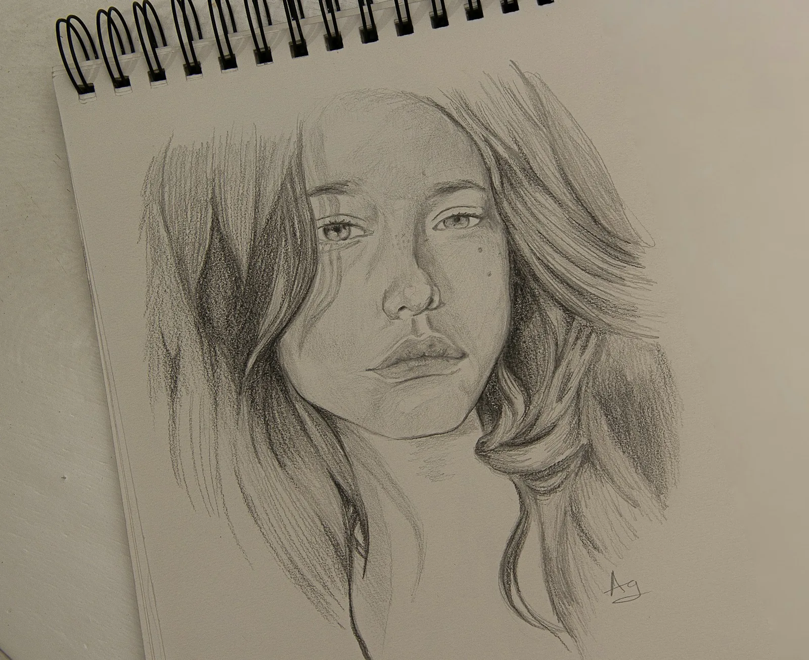 Pencil portrait sketch of a woman in a spiral sketchbook